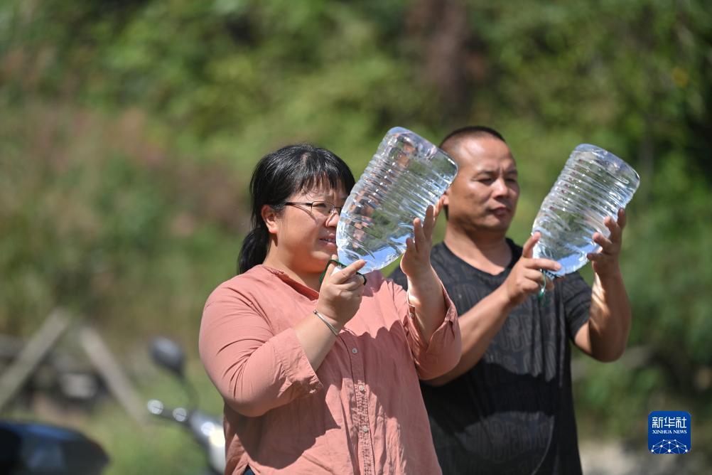 楊寧（左）在查看村民剛剛采集的水樣，為山泉水引水工程做準備（10月8日攝）。新華社記者 黃孝邦 攝